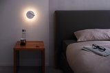 Moderner weißer LED-Wandleuchter mit Leselicht über Nachttisch aus Holz im Schlafzimmer.