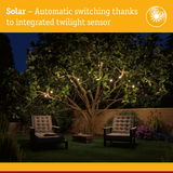 Solar garden lights with integrated twilight sensor illuminating tree and seating area at night
