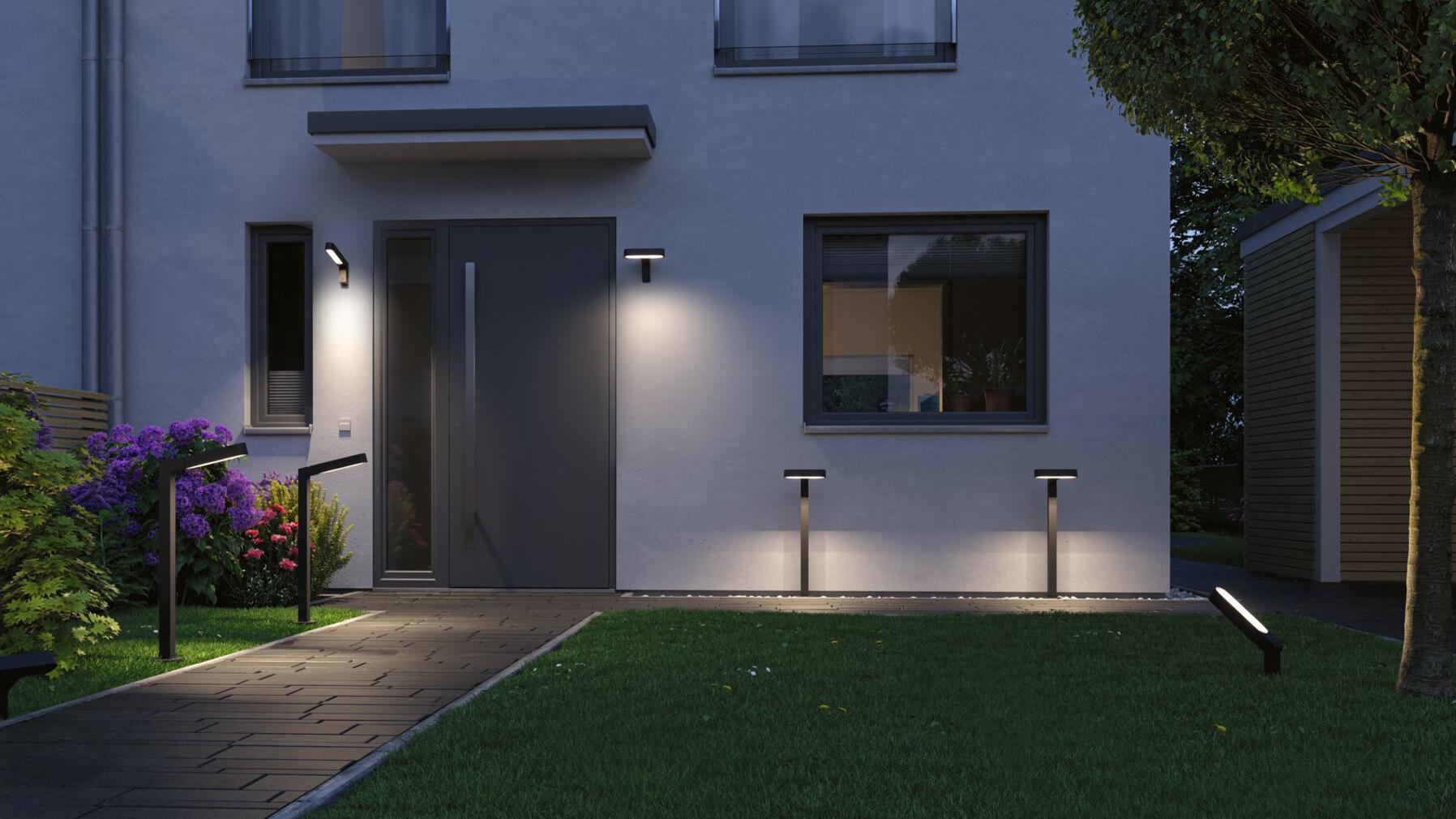 Modernes Haus mit grauer Fassade und schwarzer LED-Außenbeleuchtung an Tür und Gartenweg.