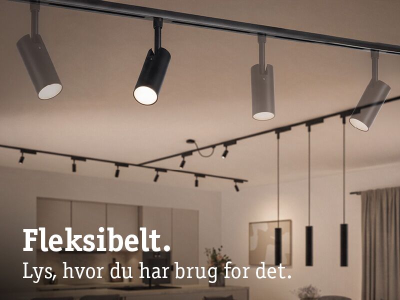 Sorte fleksible LED-skinnespotter og pendler i moderne stue med varmt lys.
