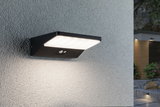 Black LED outdoor wall light with motion sensor mounted on grey wall illuminating modern entrance