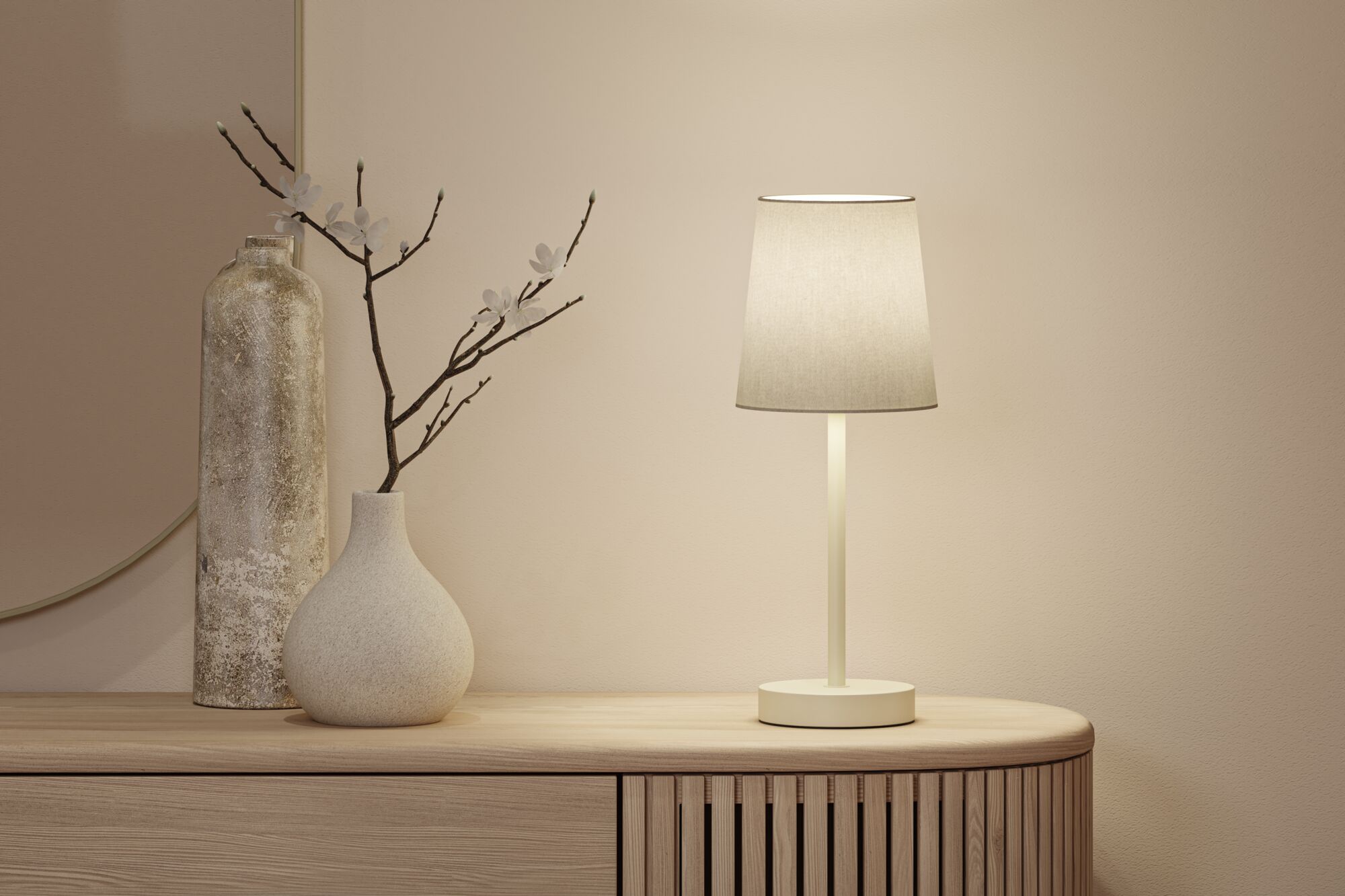 Beige table lamp with fabric shade on wooden sideboard next to two decorative vases in neutral tones