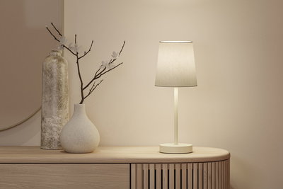 Beige Tischlampe mit Stoffschirm auf Holzkommode neben zwei dekorativen Vasen in neutralen Farben