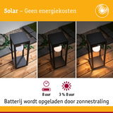 Zwarte solar buitenlamp op houten terras met batterij- en verlichtingstijd voor energiezuinige tuinverlichting