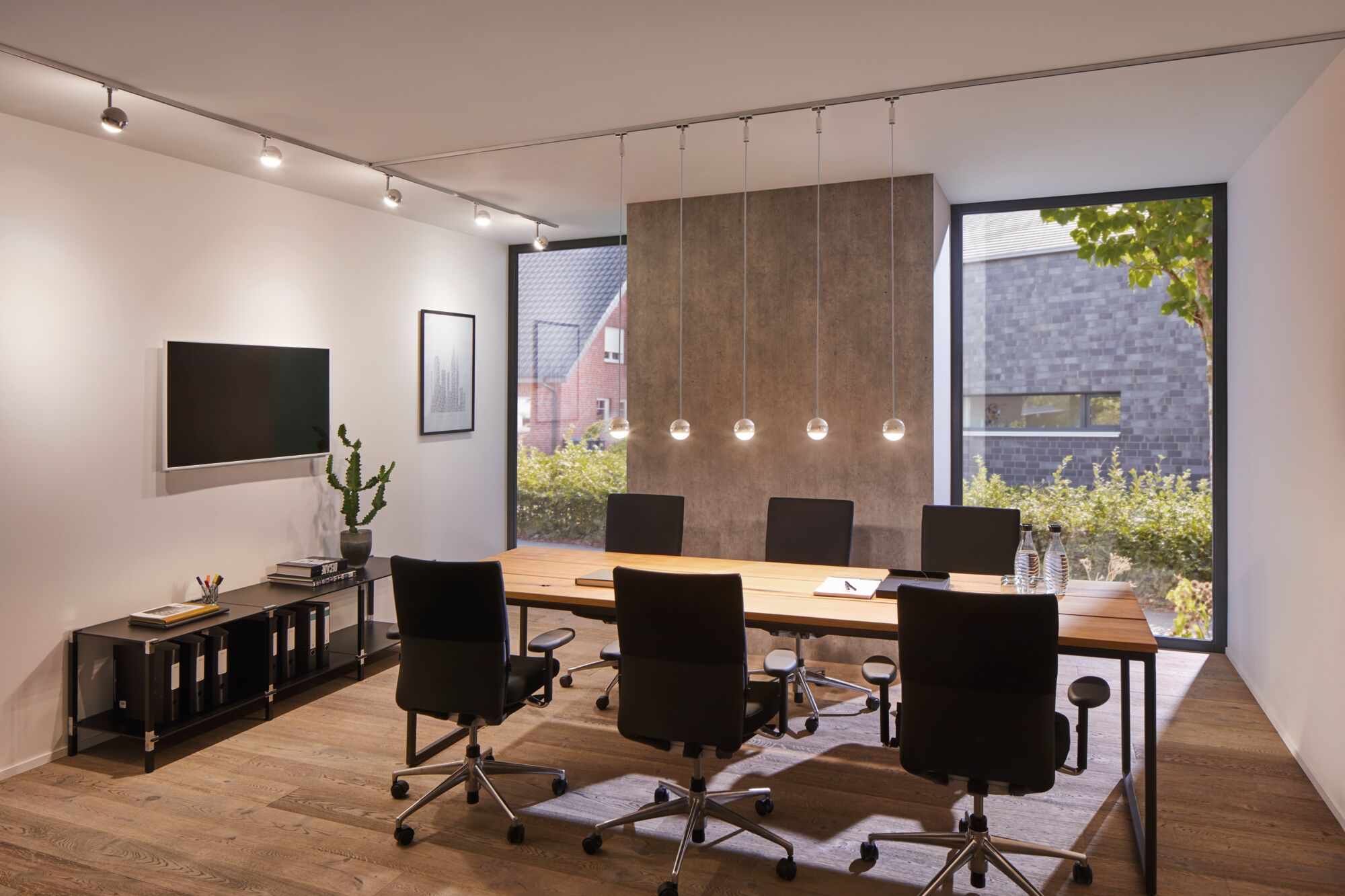 Moderne vergaderruimte met houten tafel, zwarte bureaustoelen en Paulmann VariLine LED-plafondspots.
