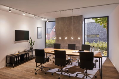Moderne vergaderruimte met houten tafel, zwarte bureaustoelen en Paulmann VariLine LED-plafondspots.