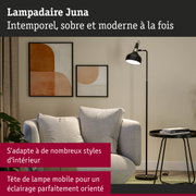 Lampadaire noir Juna avec tête mobile à côté d’un canapé gris et tableaux abstraits au mur