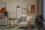 Schwarze Stehleuchte aus Metall neben grauem Sessel mit Kissen in modernem Wohnzimmer mit Pflanzen