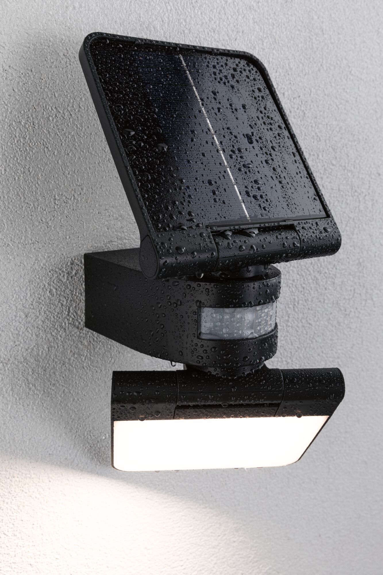 Schwarze Solar-LED-Außenleuchte mit Bewegungsmelder und wasserdichtem Gehäuse an weißer Wand.