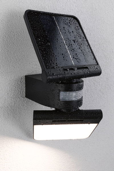 Schwarze Solar-LED-Außenleuchte mit Bewegungsmelder und wasserdichtem Gehäuse an weißer Wand.