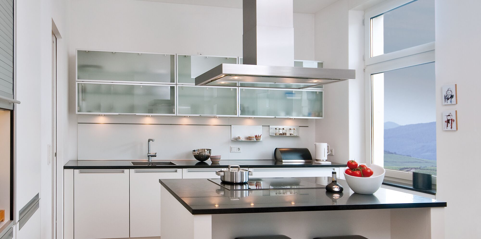 Cuisine blanche moderne avec plan de travail noir et hotte en acier inoxydable, éclairage de cuisine inclus
