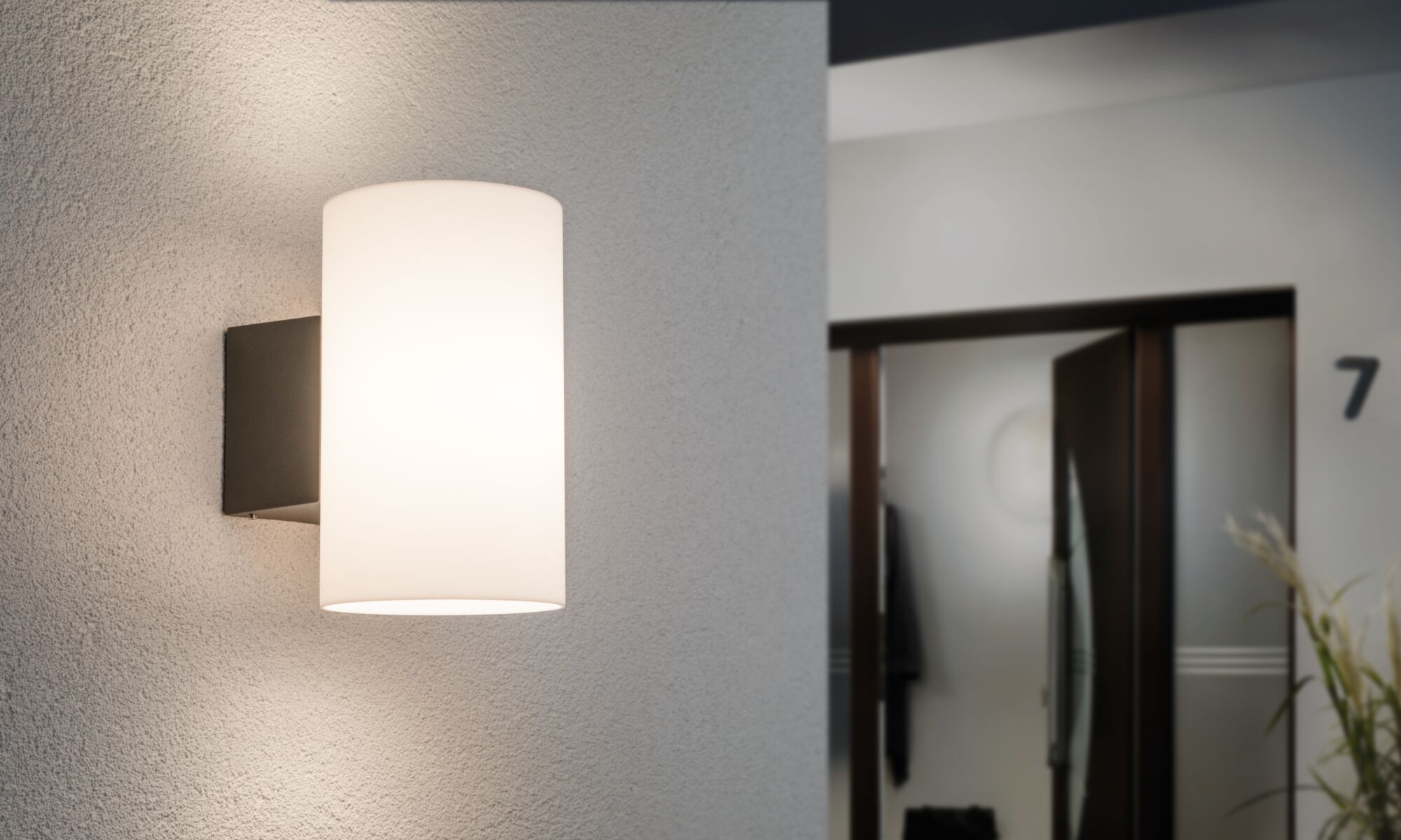 Moderne wandlamp met witte glazen kap en zwarte metalen houder voor binnenverlichting.