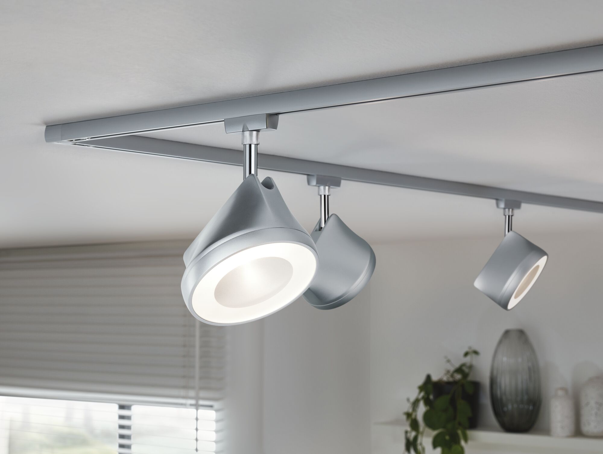Moderne Deckenstrahler aus silbernem Metall mit LED-Beleuchtung an Schienensystem für Wohnräume
