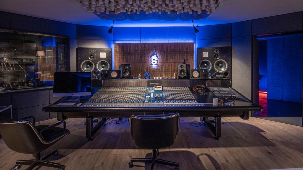 Modernes Tonstudio mit großem Mischpult, Lautsprechern und blauer LED-Beleuchtung für Musikproduktion.
