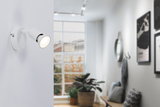 Modern white metal LED wall spotlight in hallway with window and plants, indoor lighting