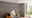 Moderne woonkamer met bruine stoffen bank, zwarte kussens en vijf hangende gloeilampen als verlichting.