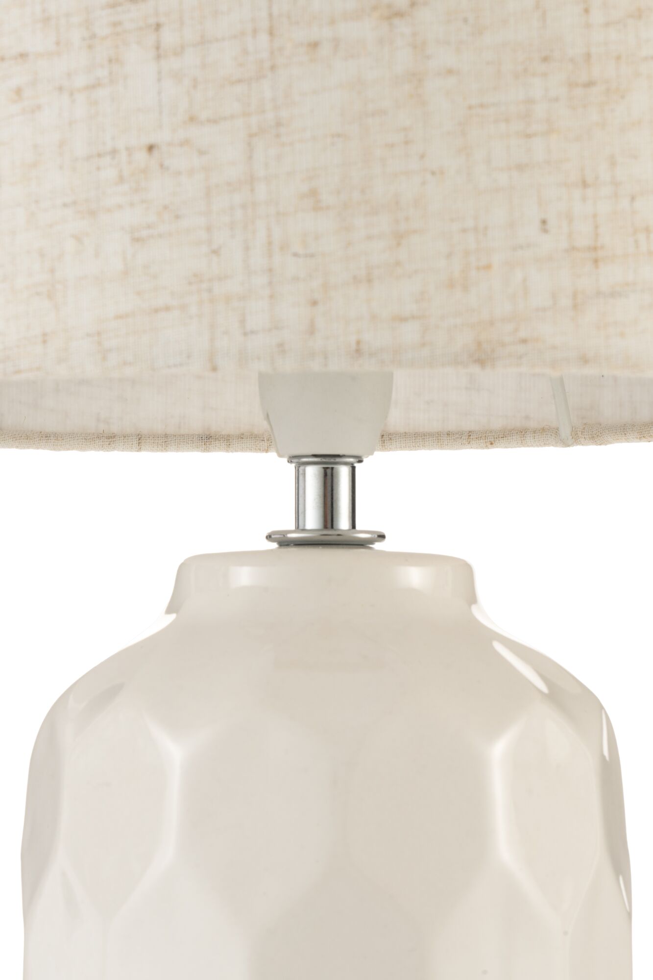 Close-up of white ceramic lamp with geometric pattern and light fabric lampshade