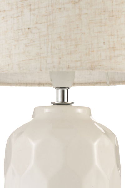 Close-up of white ceramic lamp with geometric pattern and light fabric lampshade