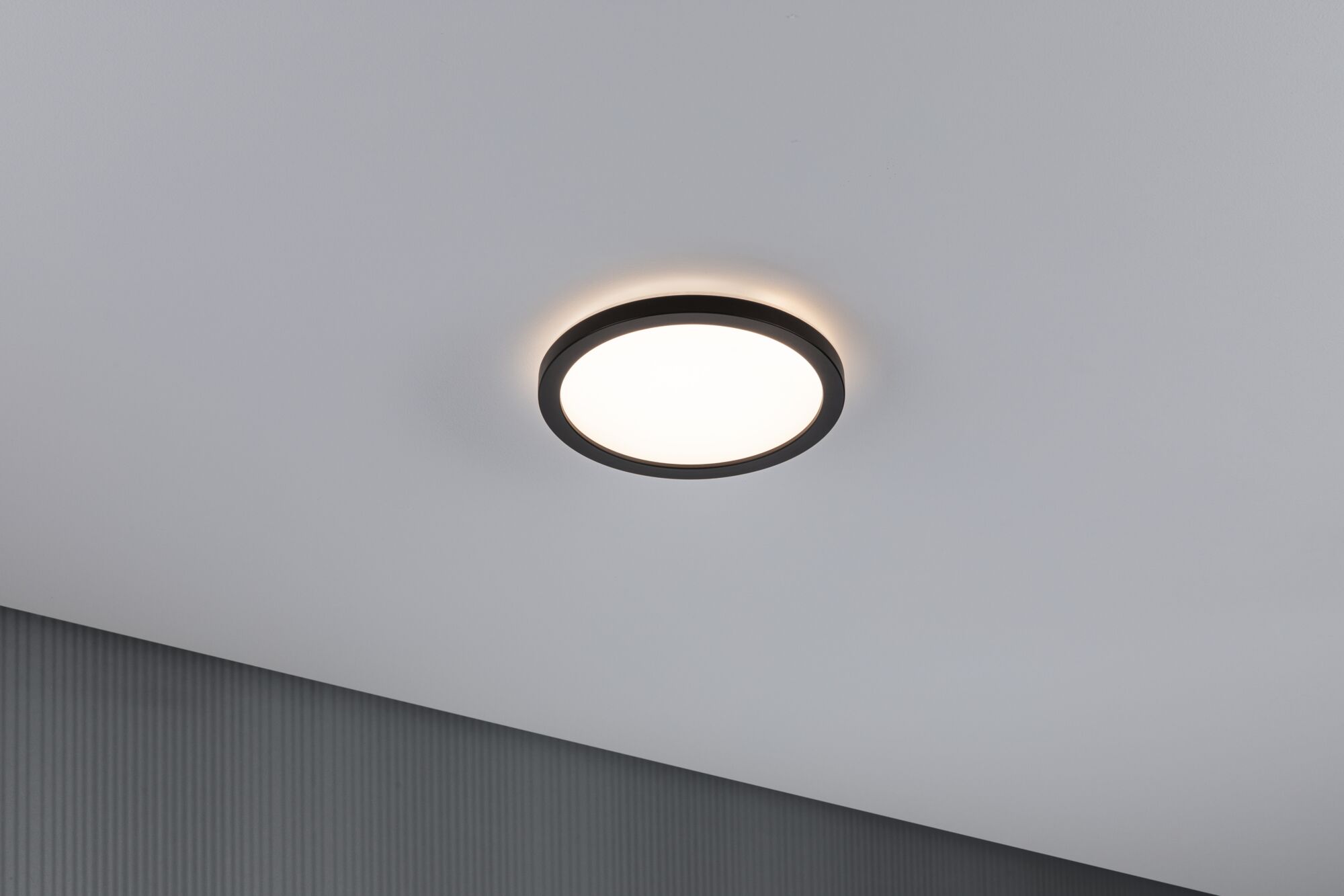 Round LED ceiling light with black metal frame and warm white light for modern interiors