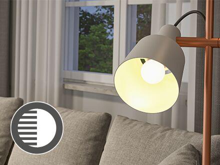 White table lamp with warm white light beside grey sofa, icon indicating flicker-free LED lighting.