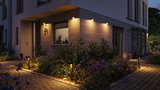 Modern outdoor lighting with warm white light on house facade and stone-paved garden path.