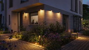Modern outdoor lighting with warm white light on house facade and stone-paved garden path.