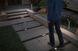 Modern square LED floor lights illuminate grey outdoor path with steps and garden bed.