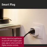 White plastic smart plug in socket with black cable for smart home device control and energy saving