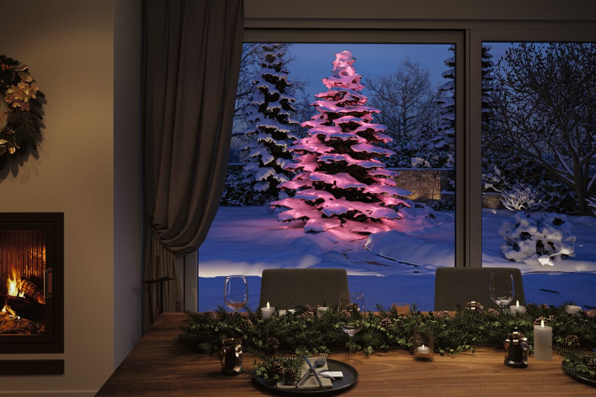 Winterliche Gartenszene mit beleuchtetem Tannenbaum in Pink und festlich gedecktem Holztisch im Innenraum