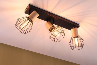 Spot plafond avec trois cages métalliques noires et détails en bois, lumière blanc chaud pour salon