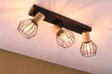 Spot plafond avec trois cages métalliques noires et détails en bois, lumière blanc chaud pour salon