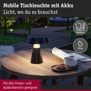 Mobile schwarze Tischleuchte mit Akku auf Holztisch im Garten, geeignet für Innen- und Außenbereich