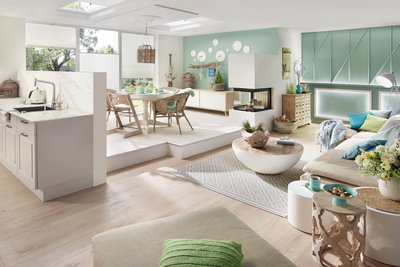 Salon lumineux avec éclairage moderne, murs turquoise, coin canapé confortable et meubles en bois et rotin.