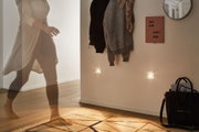 Wohnzimmer mit warmweißen LED-Nachtlichtern an Wand, Holzfußboden und Teppich mit geometrischem Muster