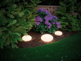 Three white LED garden globe lights illuminating flowerbed with purple blooms and green foliage.