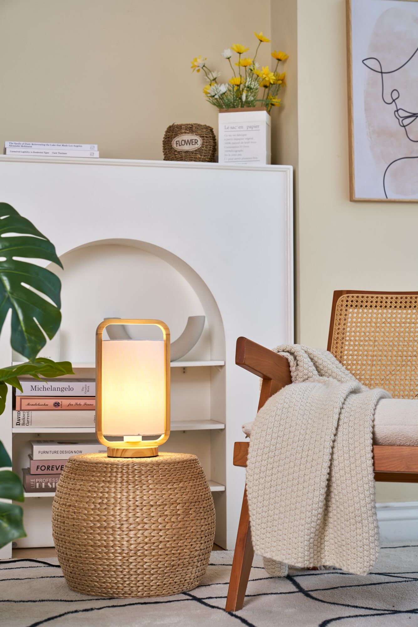 Modern table lamp with wooden frame and white fabric shade on woven side table in living room