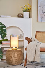 Modern table lamp with wooden frame and white fabric shade on woven side table in living room