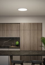 Round white LED ceiling light in modern kitchen with wood cabinets and black countertop