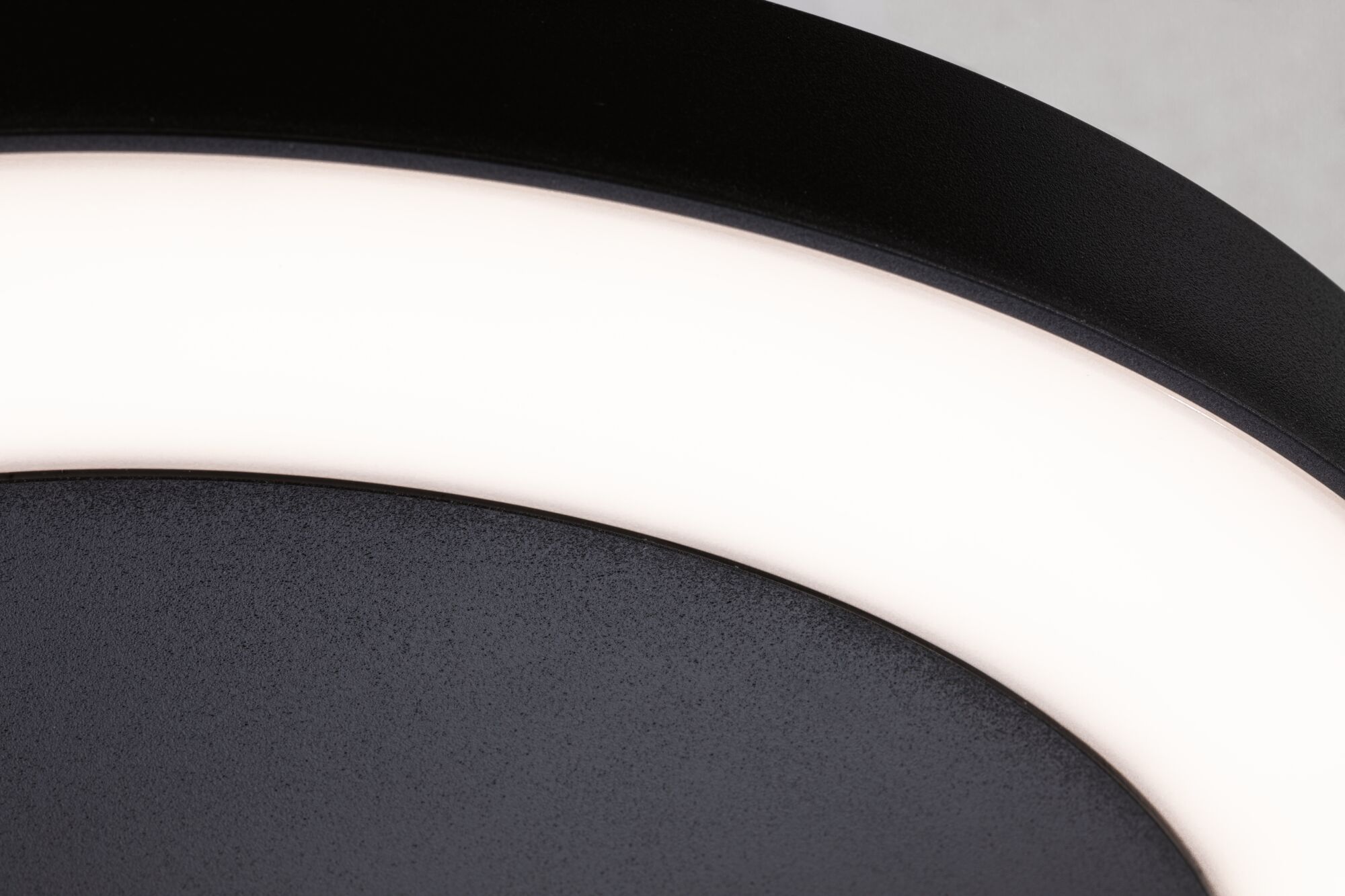 Gros plan d'un plafonnier LED noir avec anneau lumineux blanc en métal et plastique