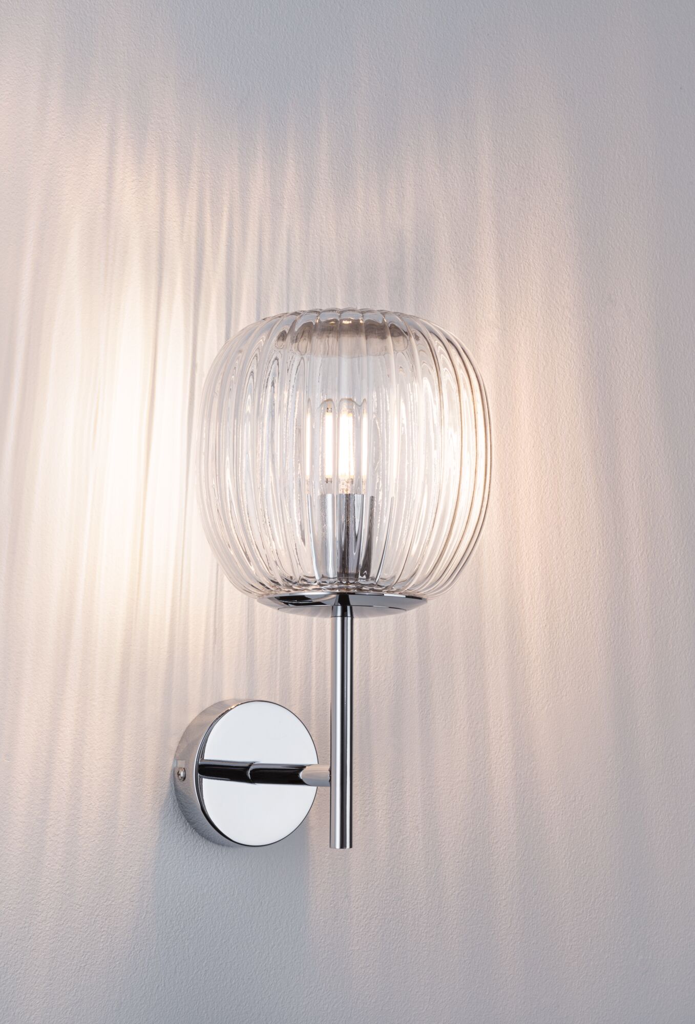 Wall lamp with ribbed clear glass and chrome metal, modern indoor lighting fixture.