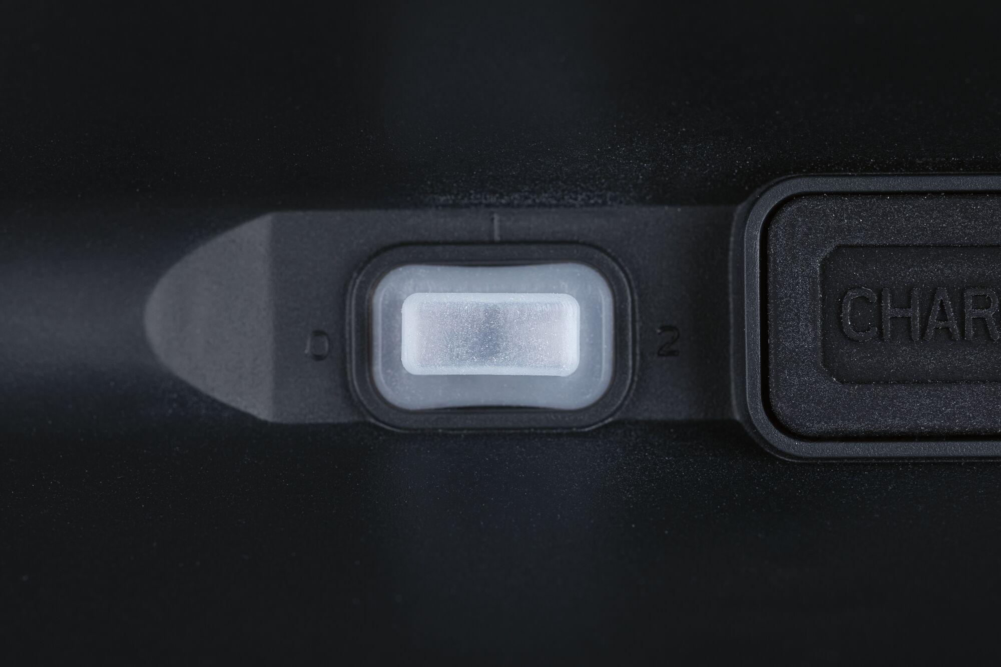 Close-up of white plastic switch on black housing with charging port next to it