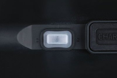 Close-up of white plastic switch on black housing with charging port next to it