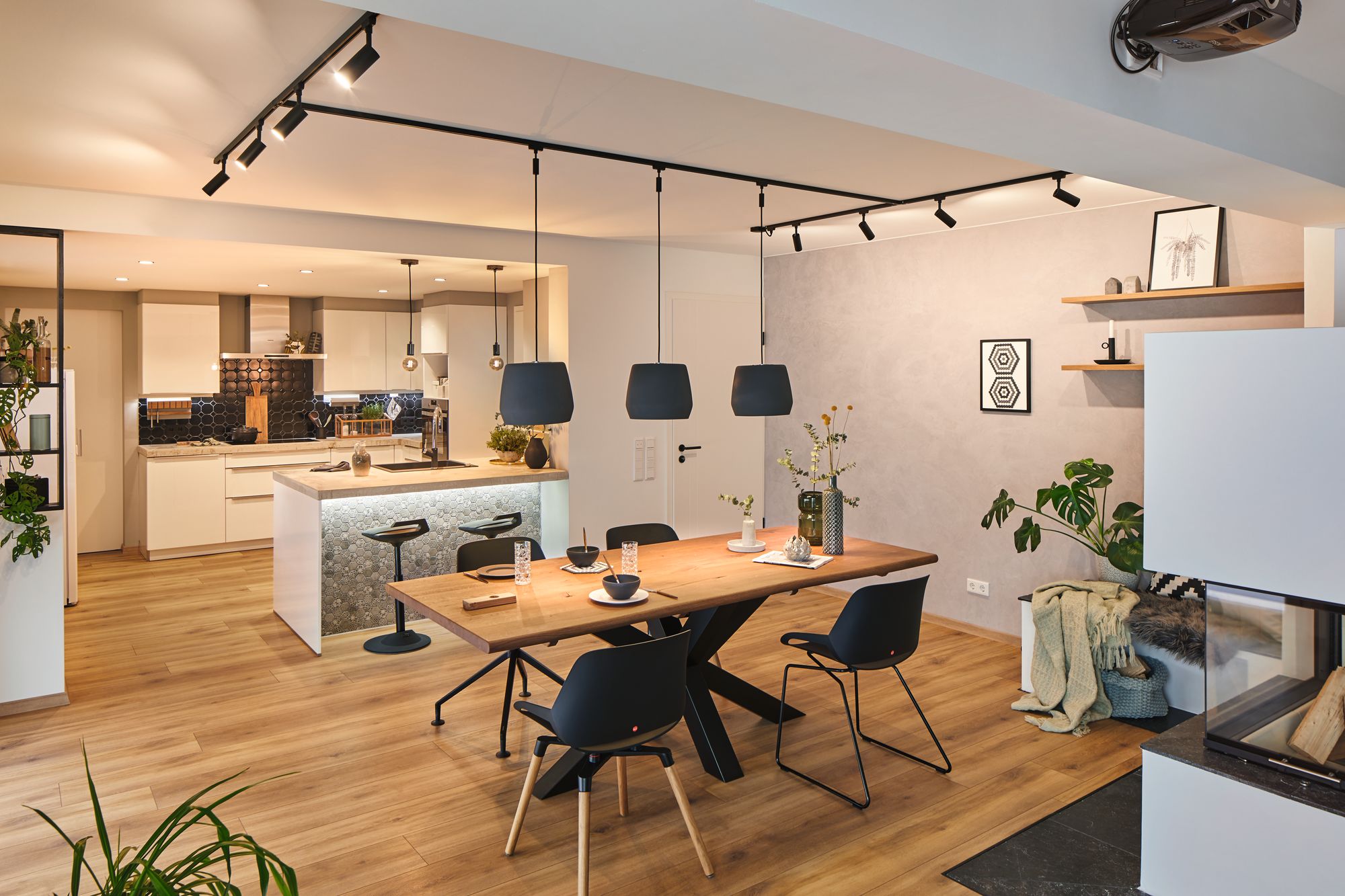 Modernes Esszimmer mit Holz-Tisch, schwarzen Stühlen und Pendelleuchten, stilvolle Wohnraumbeleuchtung.