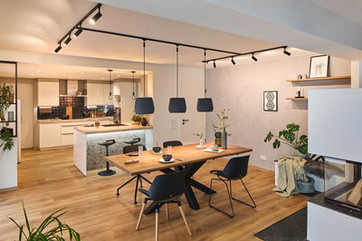 Modernes Esszimmer mit Holz-Tisch, schwarzen Stühlen und Pendelleuchten, stilvolle Wohnraumbeleuchtung.