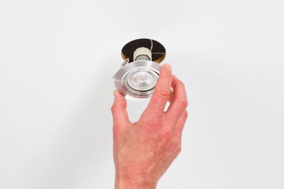 Hand installing round recessed spotlight in brushed aluminum with LED bulb in ceiling.