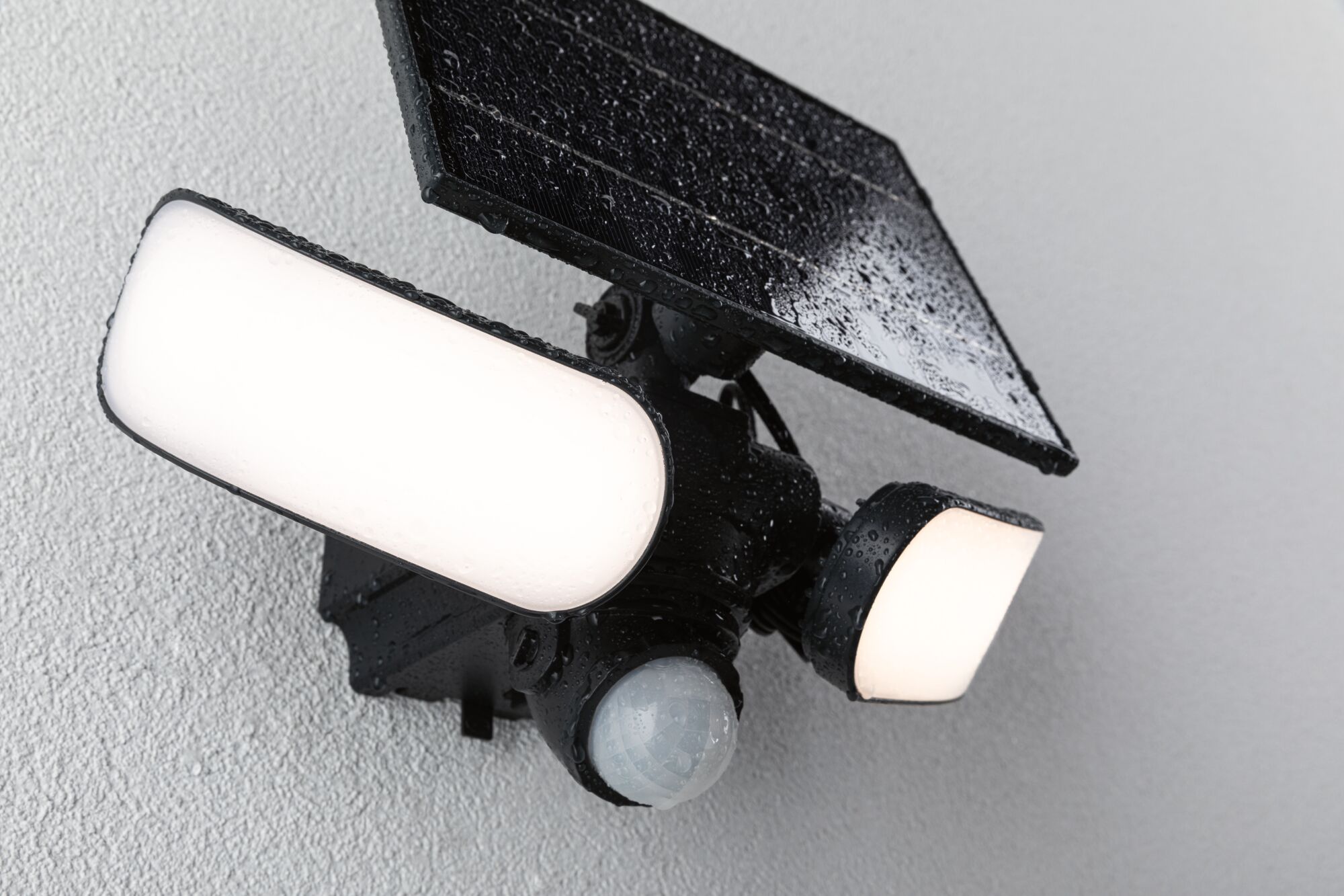 Schwarze Solar-Außenleuchte mit Bewegungsmelder und zwei weißen LED-Leuchtflächen an Wand montiert.