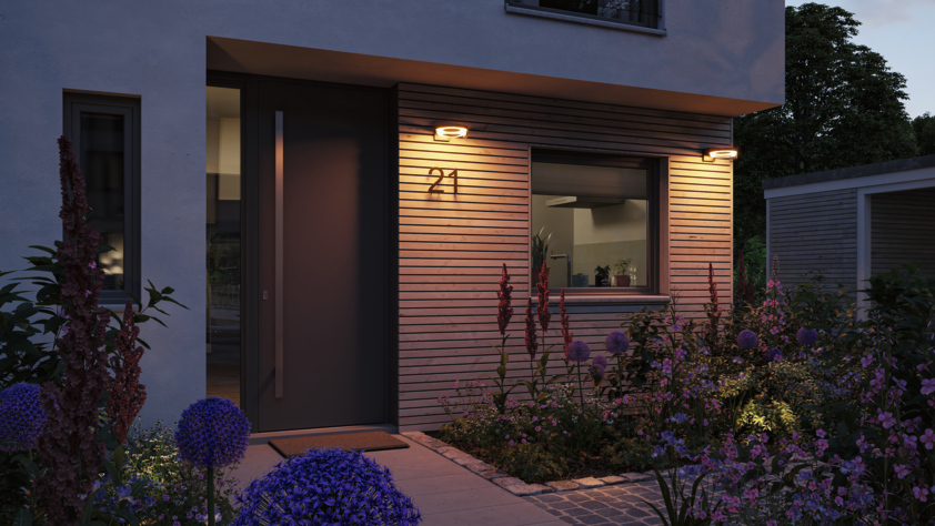 Moderne Außenwandleuchten mit warmweißem Licht an Hausfassade aus Holz und Putz bei Abendstimmung