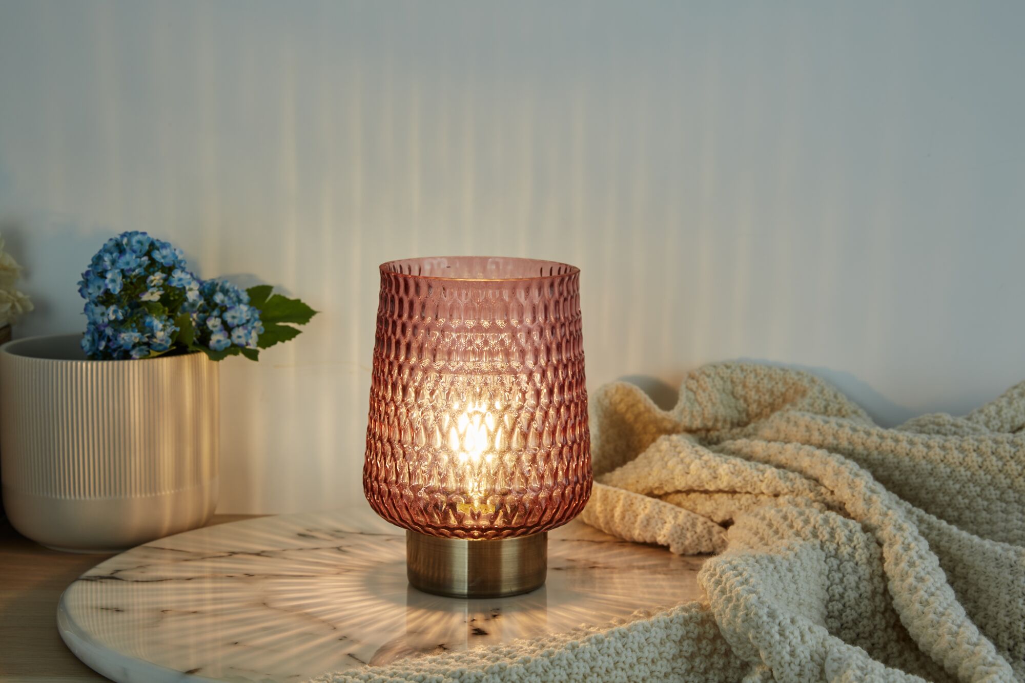 Roze glazen tafellamp met gestructureerd oppervlak en metalen voet op marmeren plaat, sfeerverlichting