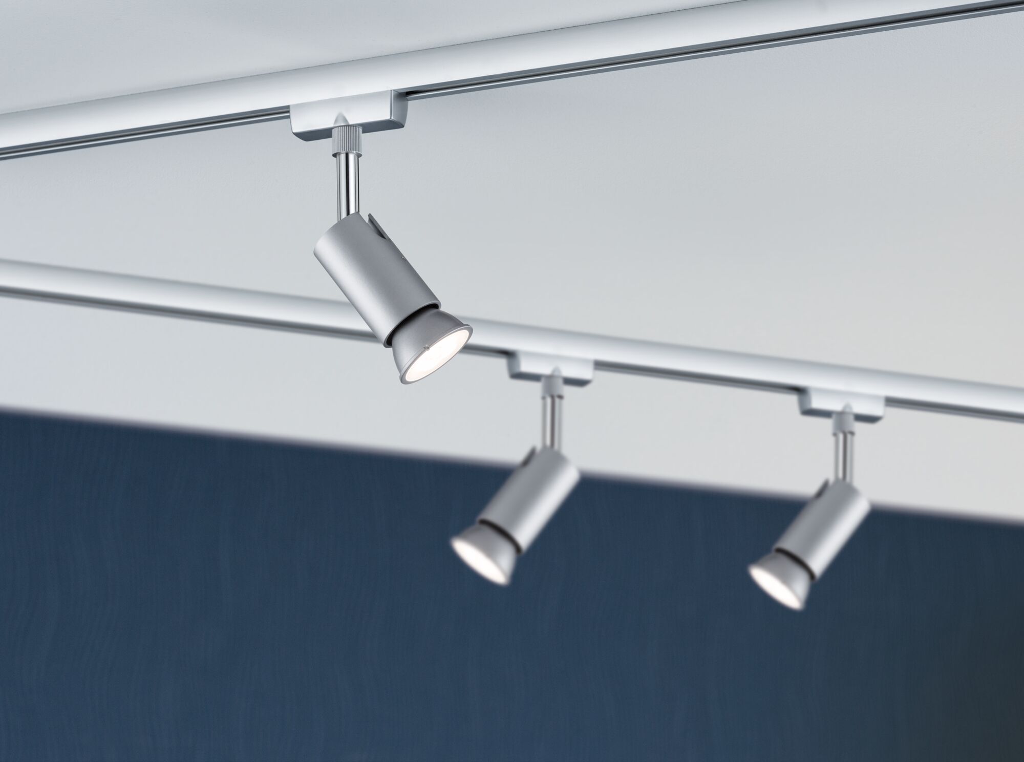 Three silver metal LED spotlights on ceiling track for modern interior lighting