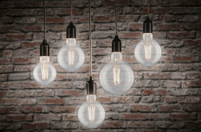 Fünf klare Glühbirnen mit Filament-LEDs vor roter Backsteinwand, warmweißes Licht 2700K